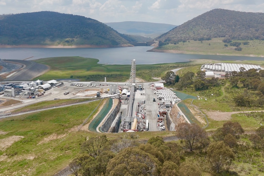 An aerial shot of a dam with construction work on the entrance to a tunnel.