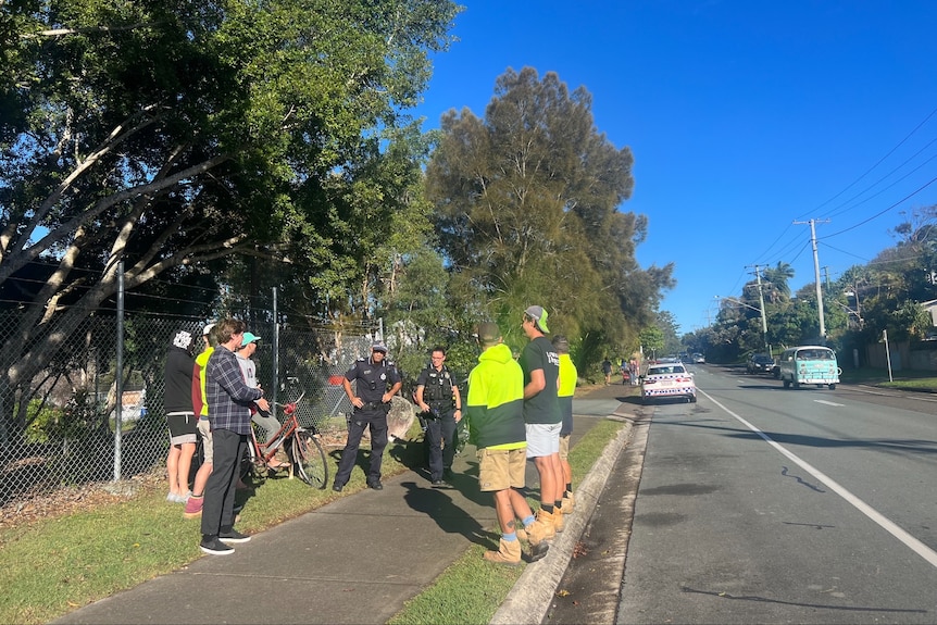 A group of tradies standing and talking to police officers