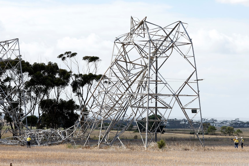 Twisted metal transmission towers under a grey sky.