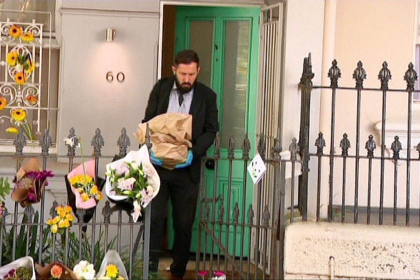 A detective carries evidence bags out of Paddington house where an elleged double murder took palce