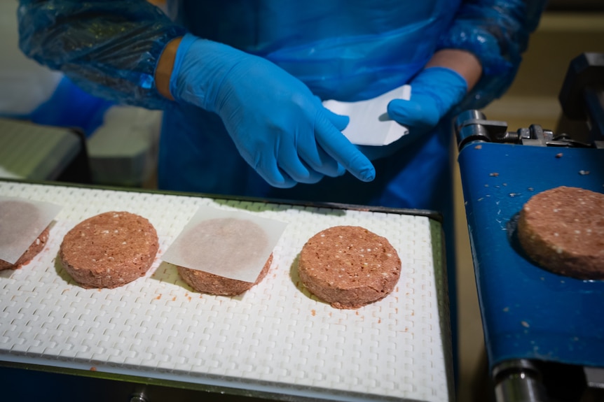 Image of pink patties on a conveyer belt.