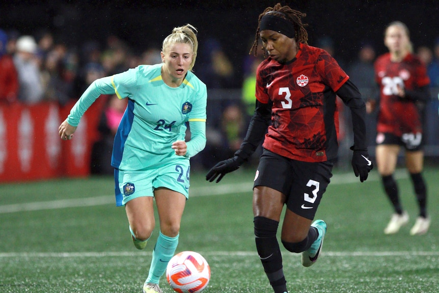 A Canadian player contests for the ball alongside an Australian opponent in a women's friendly.