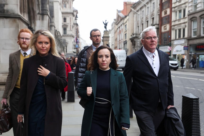 Three men and two women walking near buildings