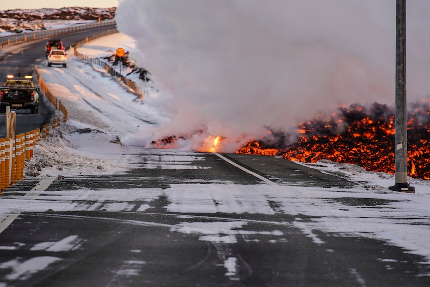 Black and orange lava sliding onto a road with some white snow