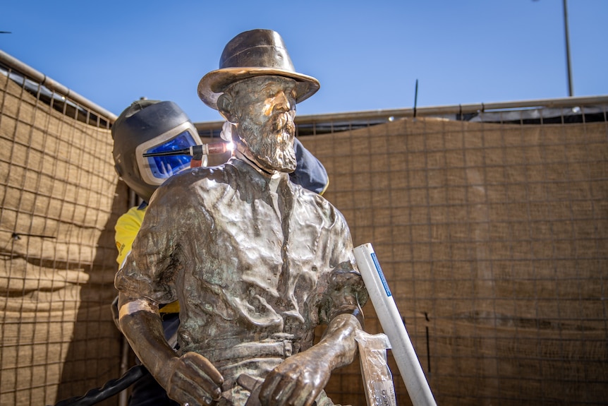 A welder working to repair a statue which was damaged by vandals.  