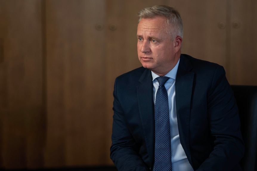 A male politician sits in a suit during an interview.