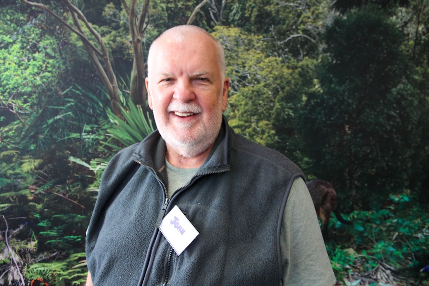 A man wearing a name tag smiles at the camera. 