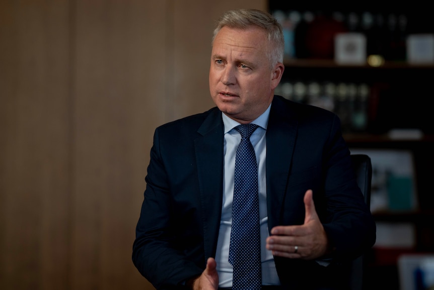 A male politician sits in a suit during an interview.