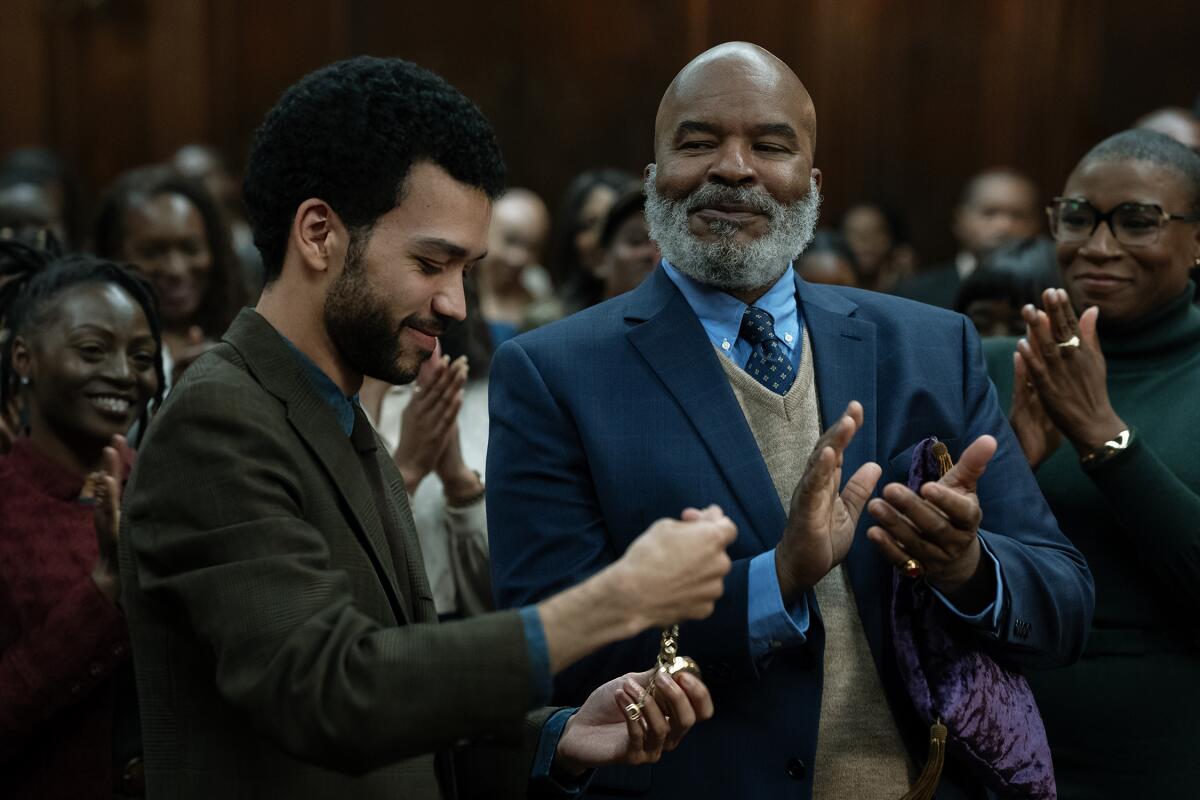 A young student is applauded by his teachers.