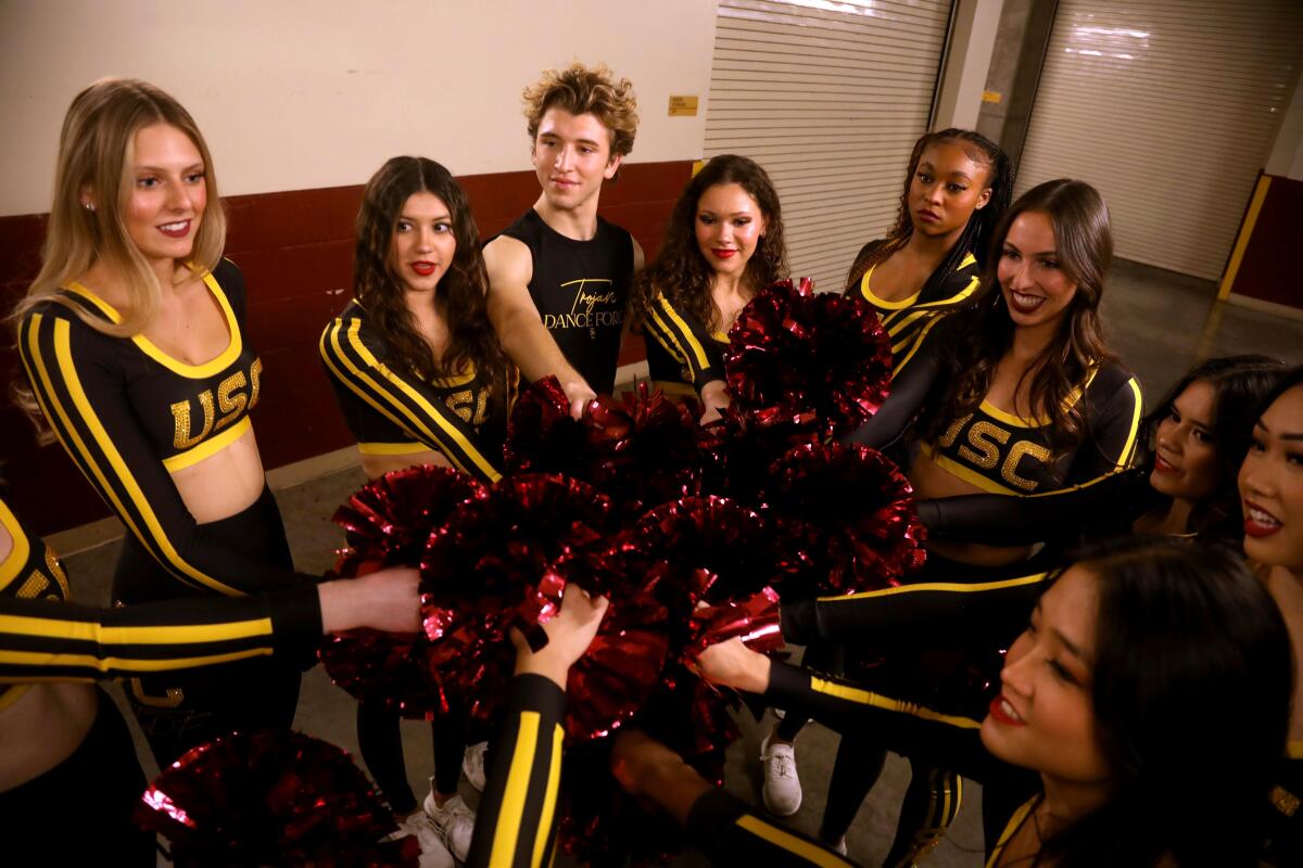 Hugo Miller, center, takes part in a pep talk with the Trojan Dance Force before a game.