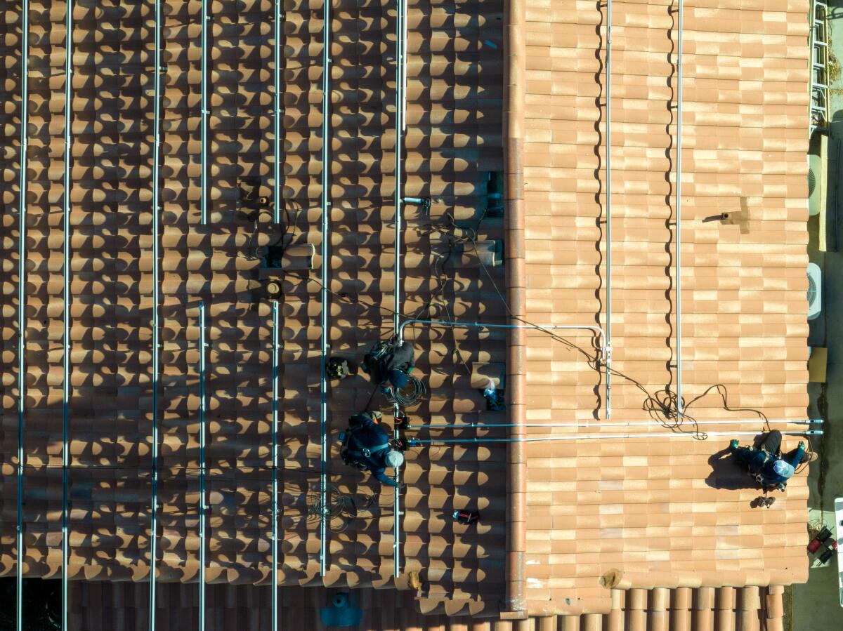 Solar panel installers are shown on a roof.