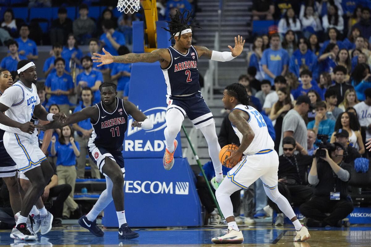 UCLA guard Sebastian Mack, right, looks to pass in front of Arizona guard Caleb Love during the first half Thursday.