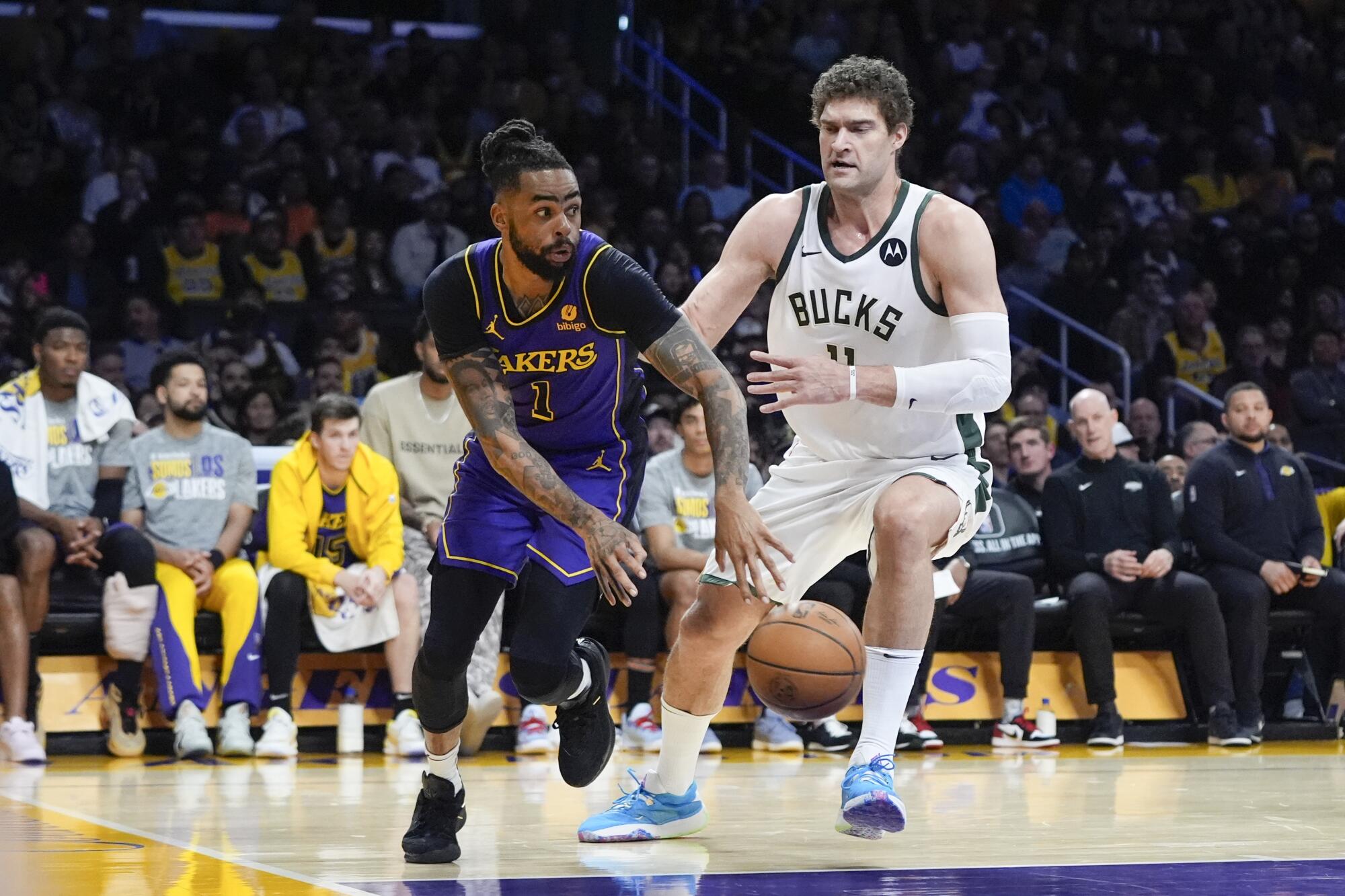 Lakers guard D'Angelo Russell, left, slips a pass around Bucks center Brook Lopez during the first half Friday night.