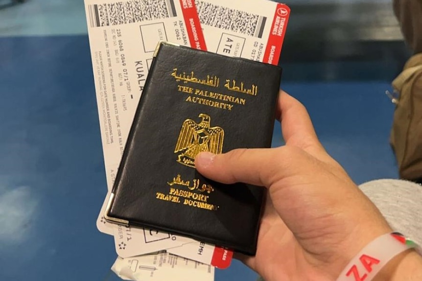 A hand holding a Palestinian passport. 