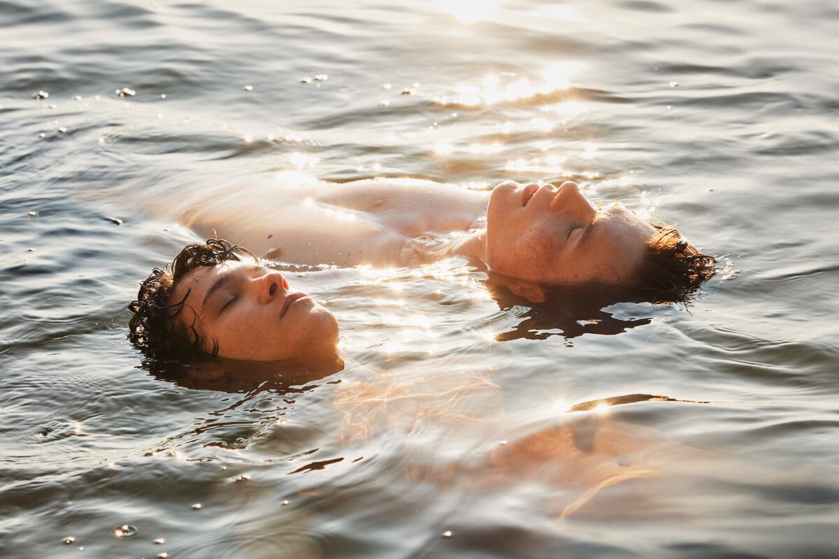 Two boys floating in the water with their heads and part of their chests visible.