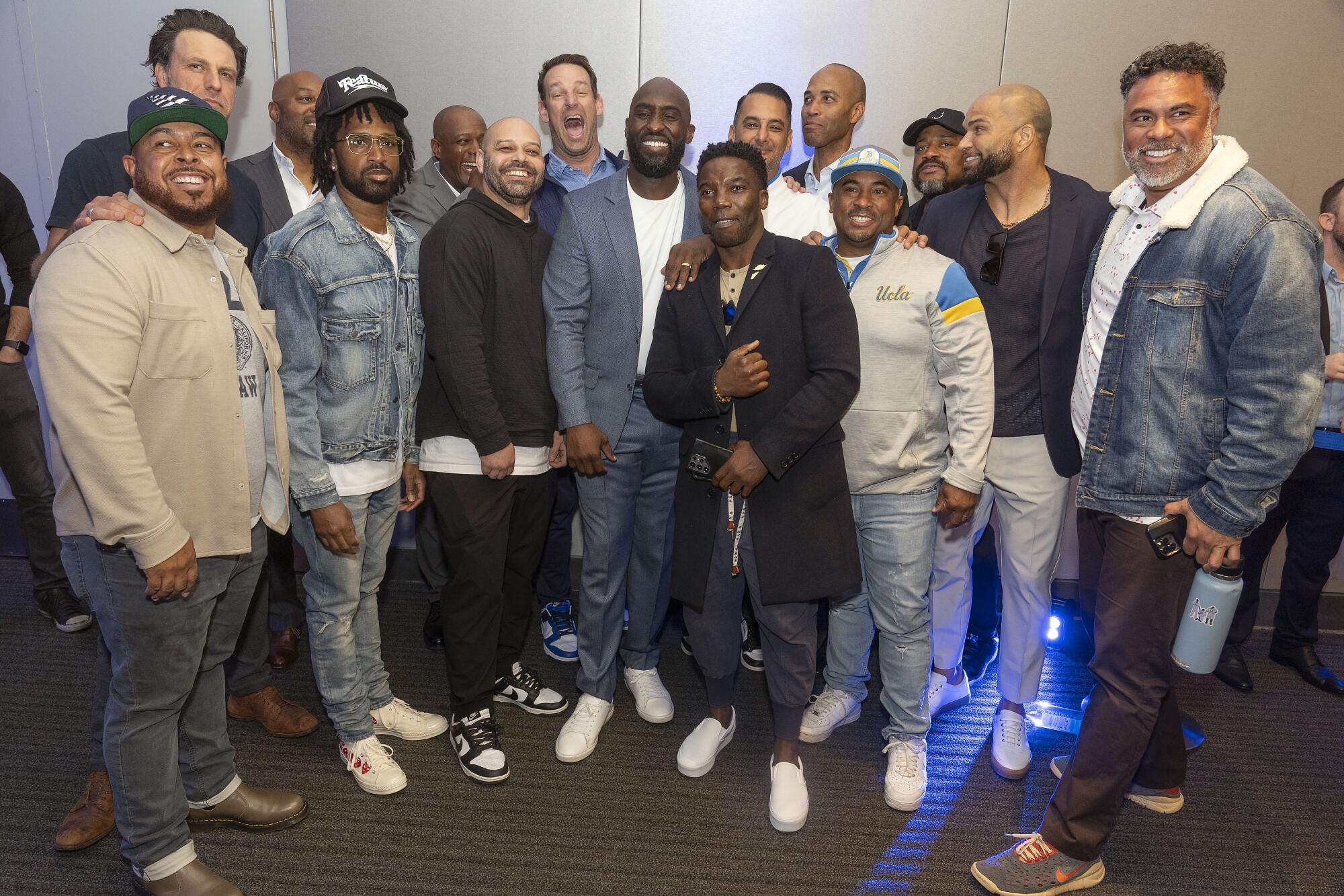 New UCLA football coach DeShaun Foster takes a group picture with former Bruins after his introductory press conference 