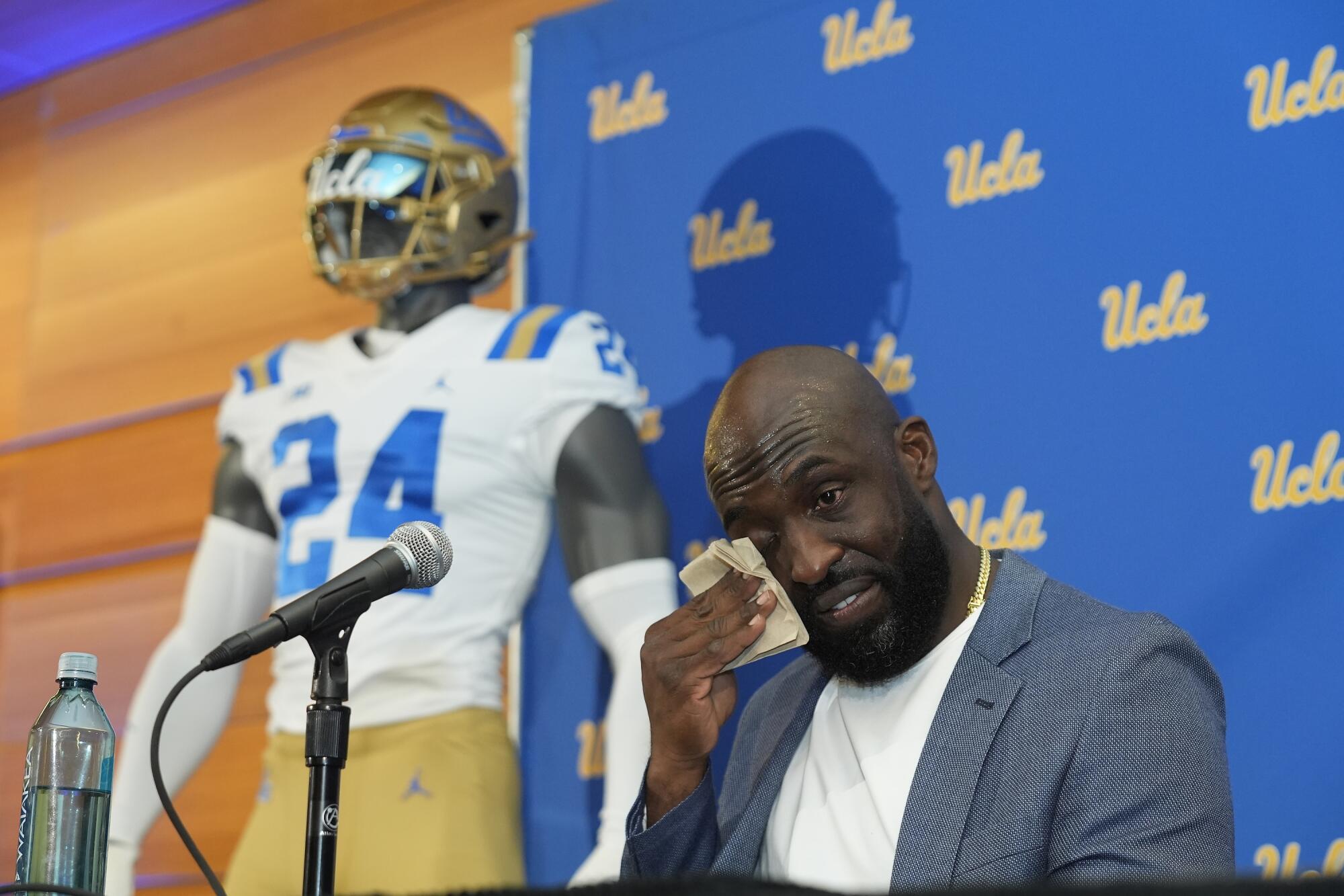 Former UCLA great DeShaun Foster wipes his face as he's introduced as the Bruins' new head football coach