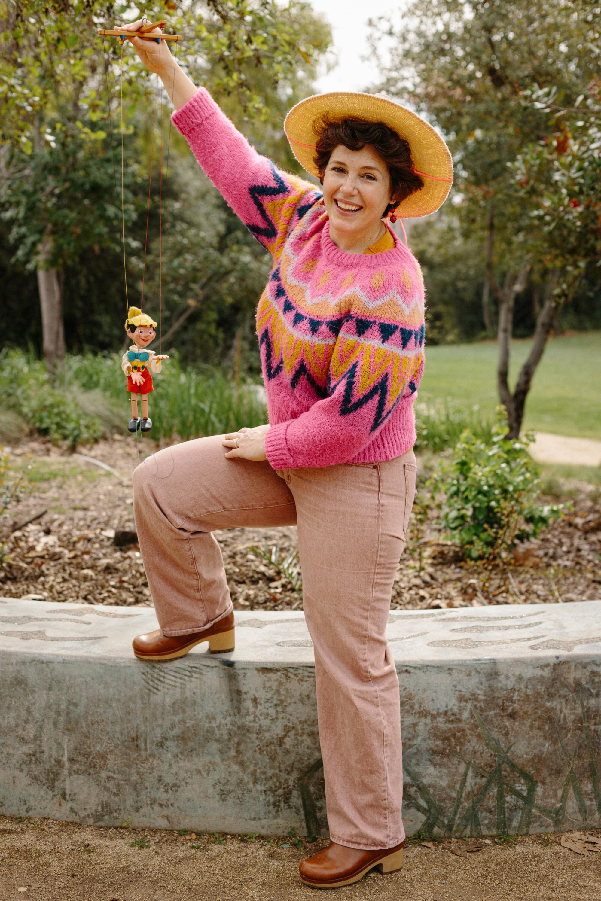 A person displays a vintage Pinocchio puppet.