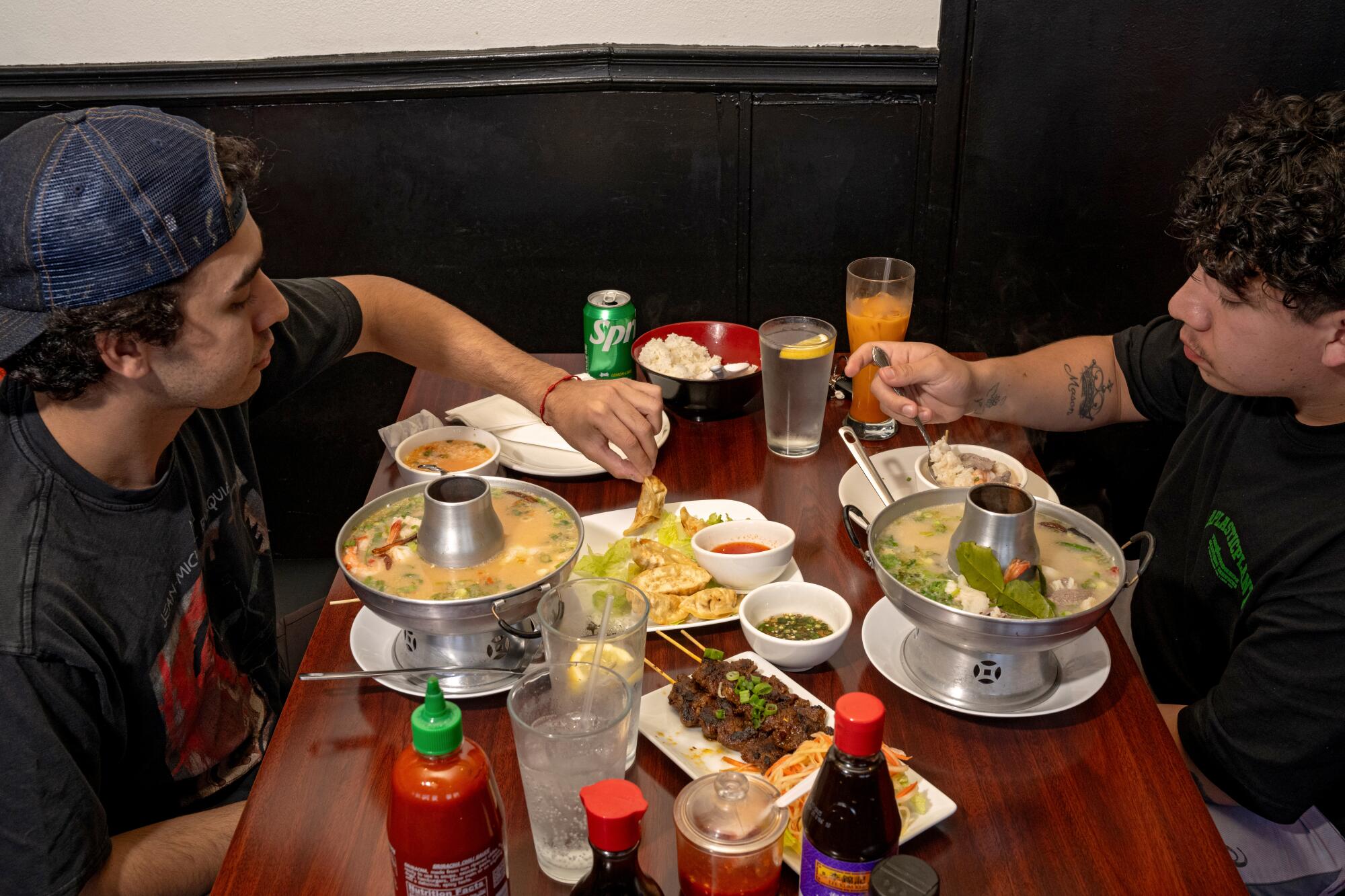 Two people face each other across a table filled with Cambodian dishes.