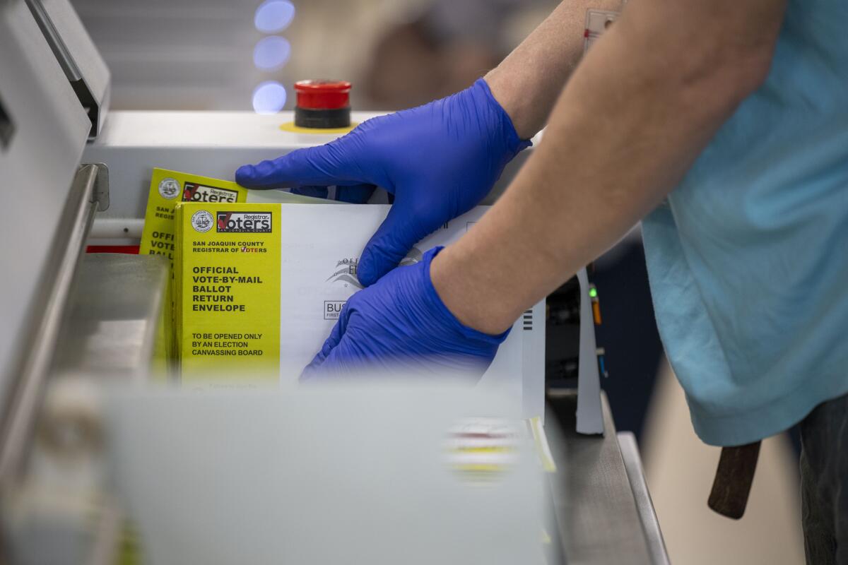 Gloved hands sort ballots at the San Joaquin County Registrar office.