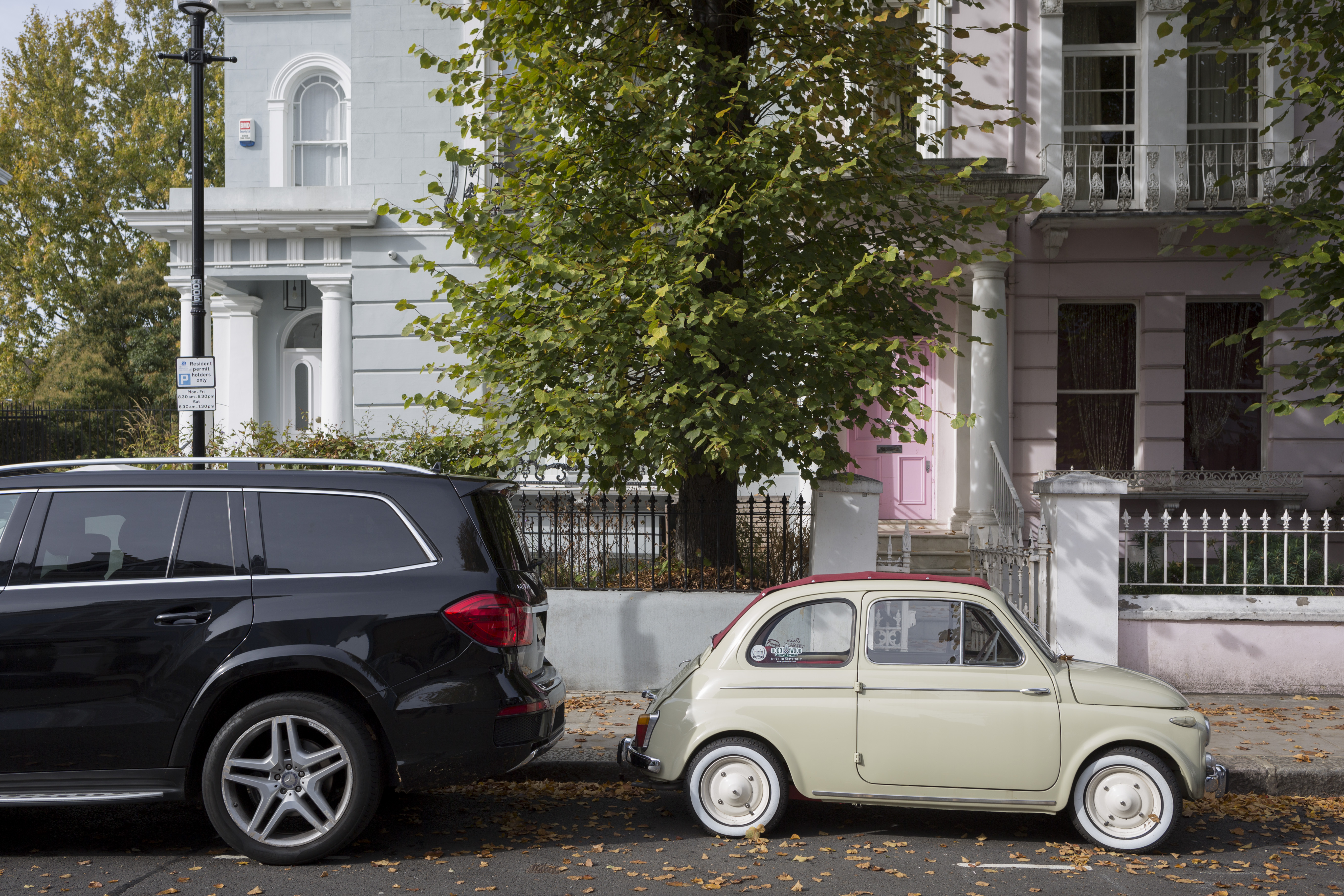 A large 4×4 SUV car parked behind a much smaller FIAT 500