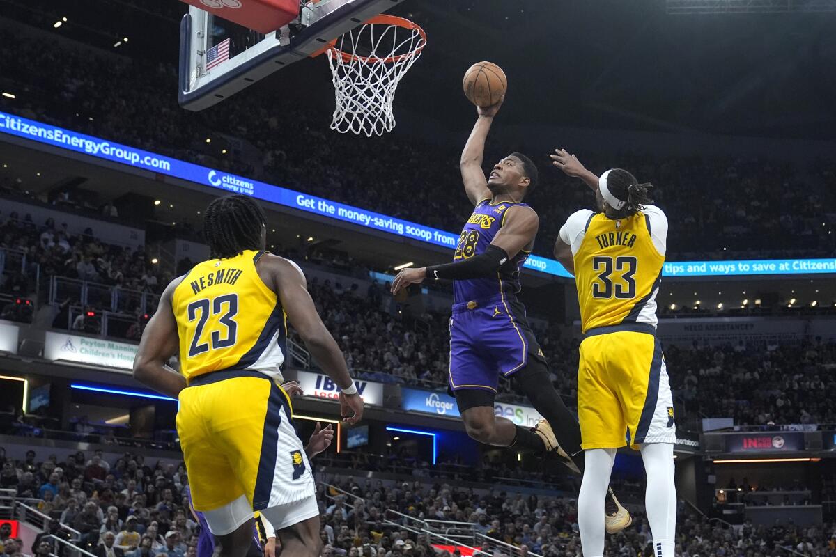 Lakers forward Rui Hachimura, center, dunks in front of Indiana's Myles Turner and Aaron Nesmith.