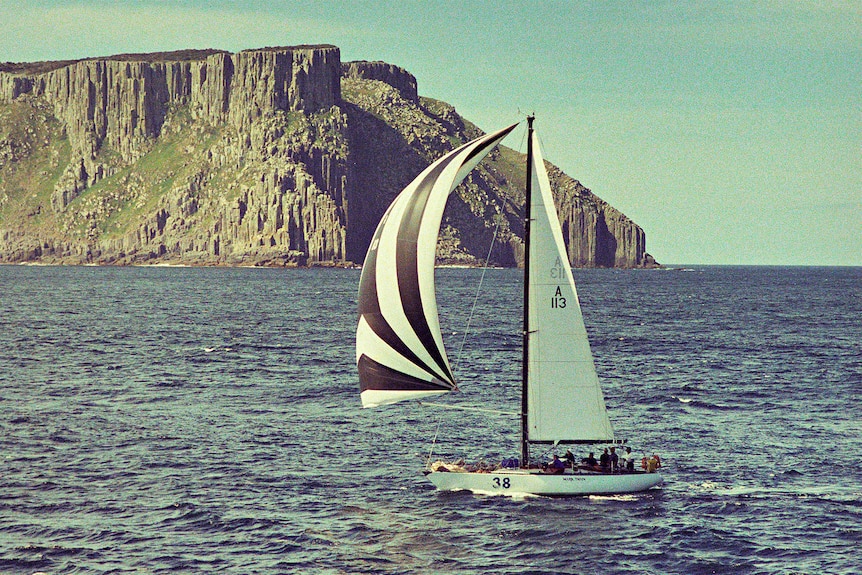 A yacht sailing past a headland.