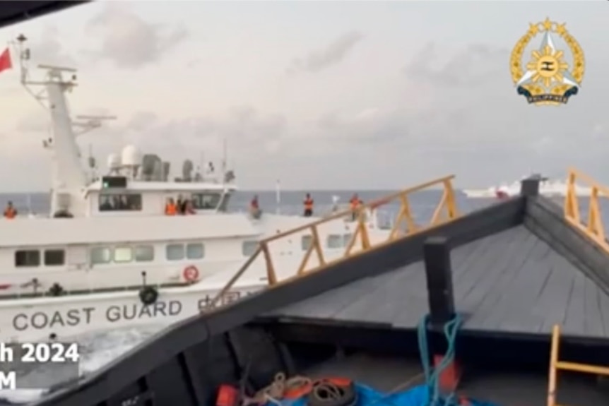 A large white ship blocks a smaller grey boat in open ocean