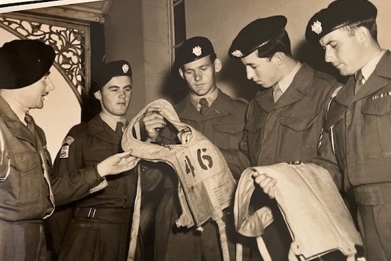 An old photo of five men in Army uniform holding life jackets.