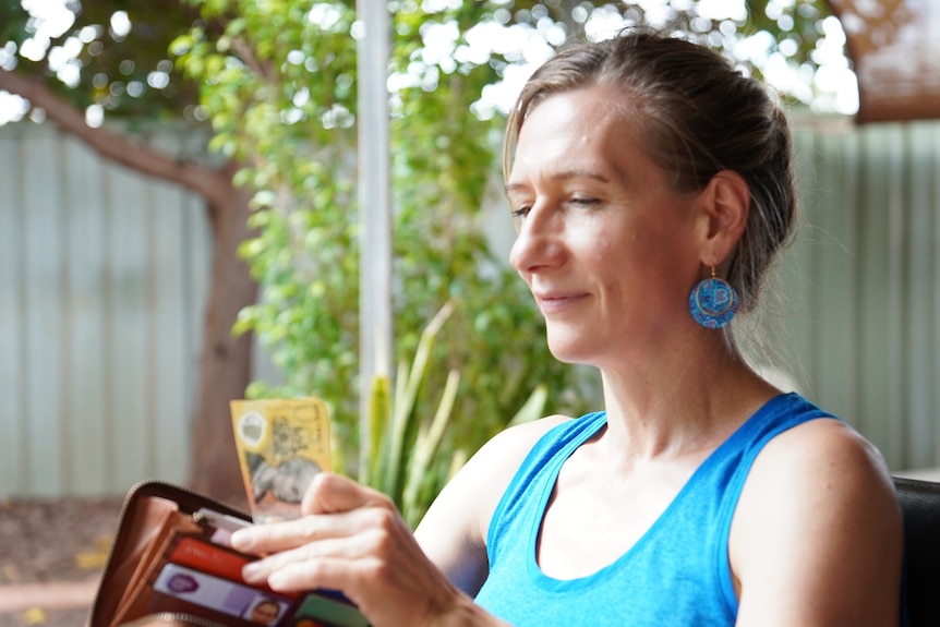 A woman pulls a fifty dollar note out of her wallet