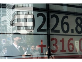 Pedestrians reflected in the windows of a securities firm in Tokyo. Photographer: Soichiro Koriyama/Bloomberg