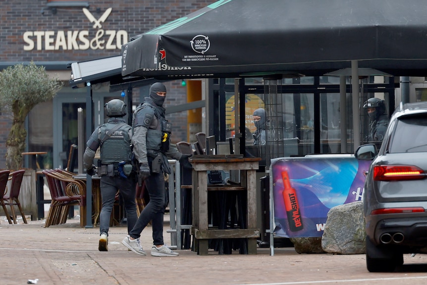 Two police covered head to toe in dark grey clothing walking into a venue