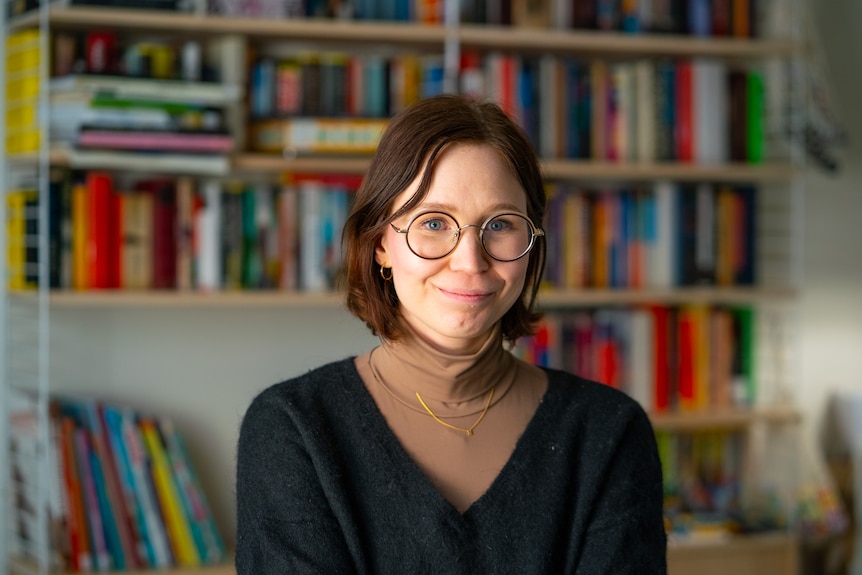 Portrait of a woman with short brown hair wearing a brown turtleneck and v-neck wool sweater.