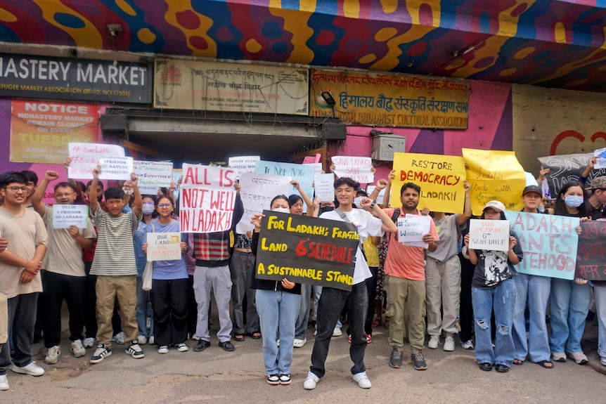 Dozens of people hold signs in a street calling for government action