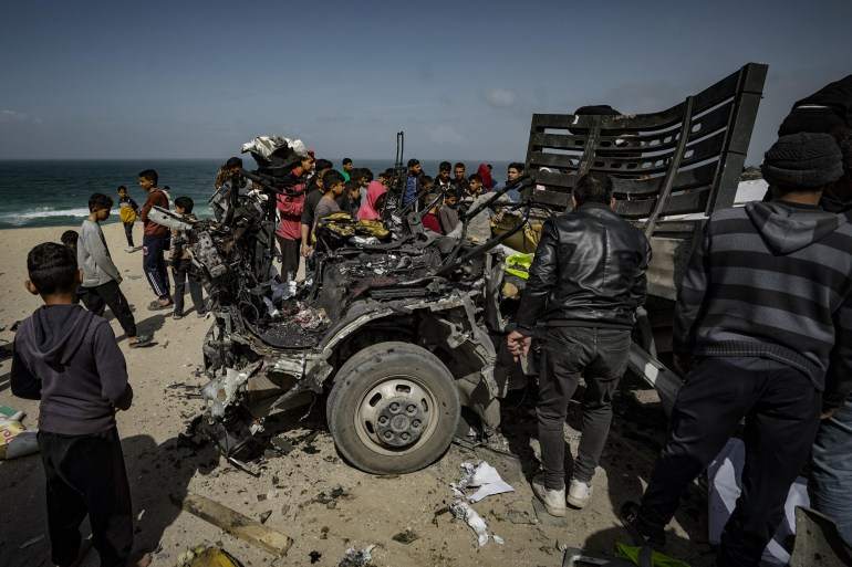 Palestinians inspect the heavily damaged humanitarian aid vehicle, which has been the target of Israeli airstrikes resulting in the death of nine and dozens of injured, in Deir al-Balah, Gaza on March 3