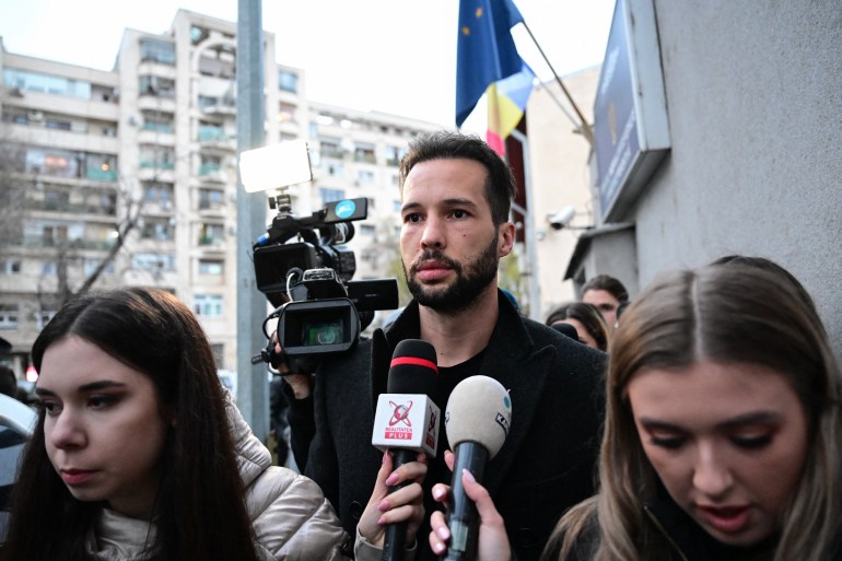 Tristan Tate (C) is followed by journalists as he and his brother British-US former professional kickboxer and controversial influencer Andrew Tate