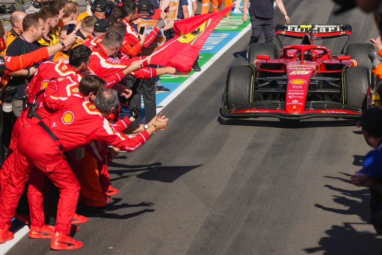 Ferrari driver Carlos Sainz of Spain steers his car into pit lane as his teammates celebrates after winning the Australian Formula One Grand Prix at Albert Park, in Melbourne, Australia, Sunday, March 24, 2024. (AP Photo/Scott Barbour)