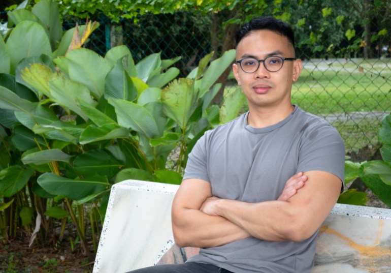 Nasha Rodziadi Khaw. He is sitting on a bench and wearing a grey T-shirt. He has his arms crossed and looks relaxed.