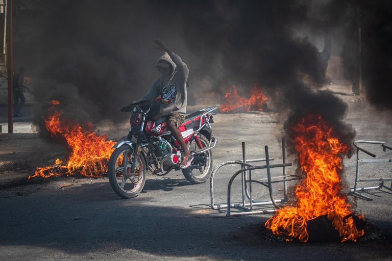 A person rides a motorcycle through street fires, in Port-au-Prince, Haiti, a day after gang violence left at least five dead and twenty injured. Caribbean Community officials plan to hold a meeting with Haitian stakeholders Monday to discuss solutions to the political violence in the island nation. Photo by Johnson Sabin/EPA-EFE