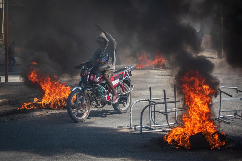 A person rides a motorcycle through street fires in Port-au-Prince, Haiti, on Friday, a day after gang violence erupted. Photo by Johnson Sabin/EPA-EFE