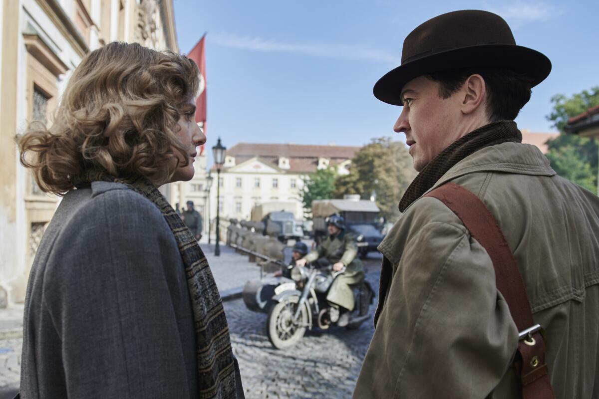 A woman speaks to a man outside during WWII.