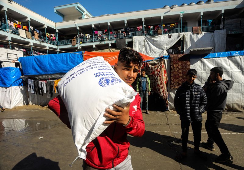 Displaced Palestinians receive flour bags at the United Nations Relief and Works Agency for Palestine Refugees school in Rafah in the southern Gaza Strip on Jan. 28. On Sunday, the United Nations announced that it had been informed by Israel that UNRWA would no longer be permitted to deliver aid to northern Gaza. File Photo by Ismael Mohamad/UPI