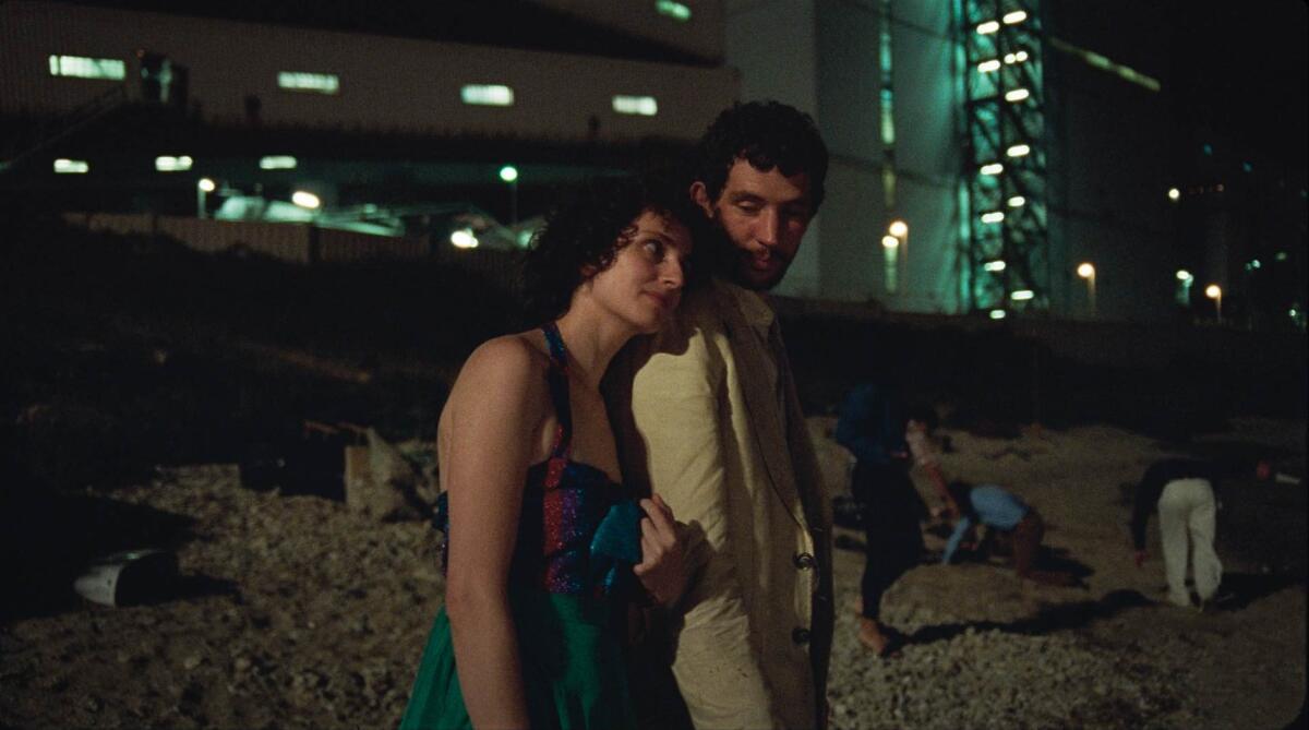 A woman and a man stand on a beach.