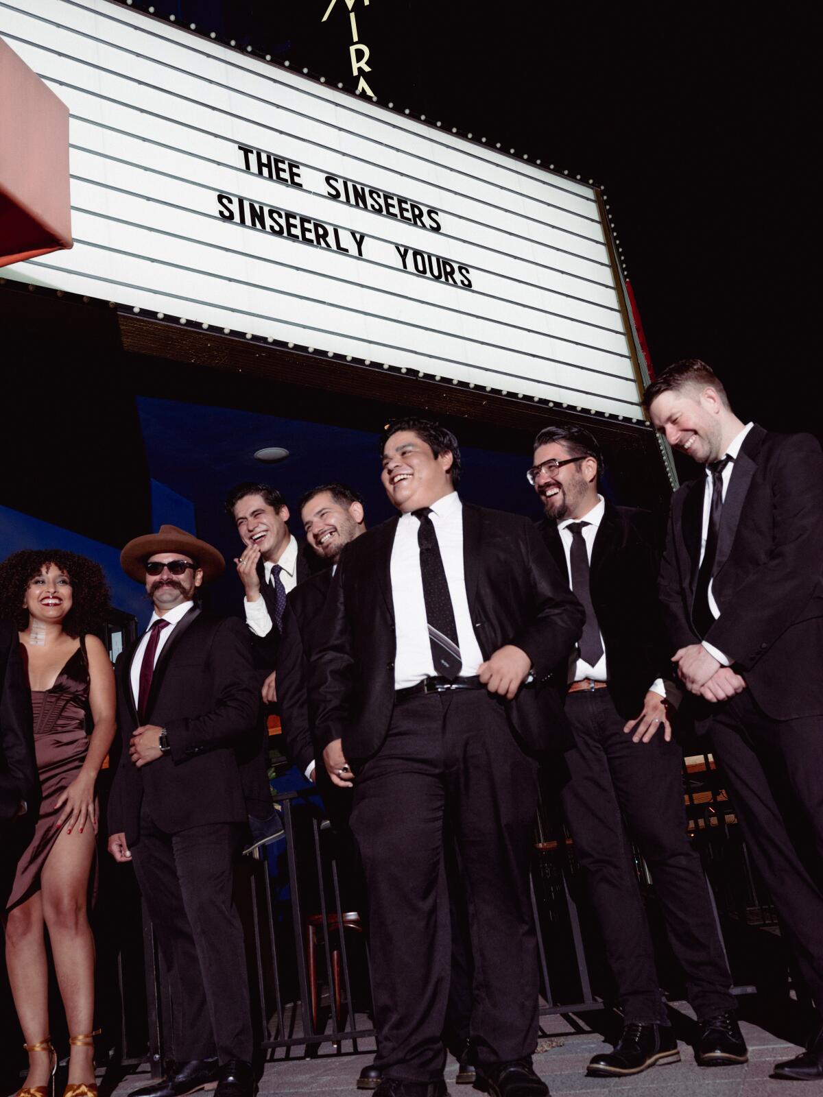 A group of band members dressed up standing outside of a marquee