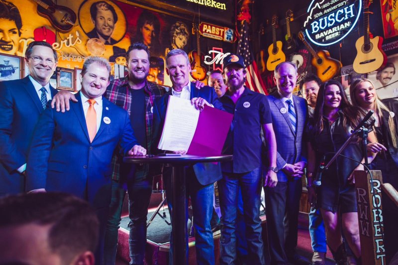 Tennessee Gov. Bill Lee (C) poses for a photo Thursday at Robert's Western World, in Nashville, Tenn., with a bill he signed to protect musicians from artificial intelligence. Photo courtesy of Tennessee Gov. Bill Lee/X