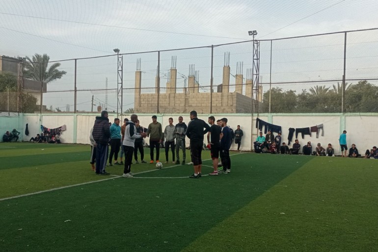 Two teams gather in the middle of the pitch before the start of a match during a Ramadan football tournament at Al-Salah Football Club in Gaza [Abubaker Abed/Al Jazeera]