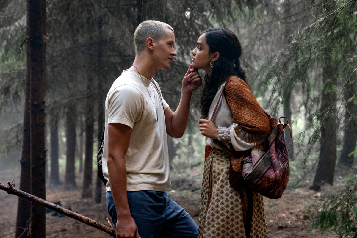 A man and a woman speak in a forest.