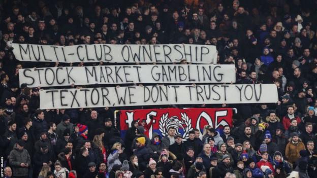 Crystal Palace fans hold up banners directed at co-owner John Textor in 2023