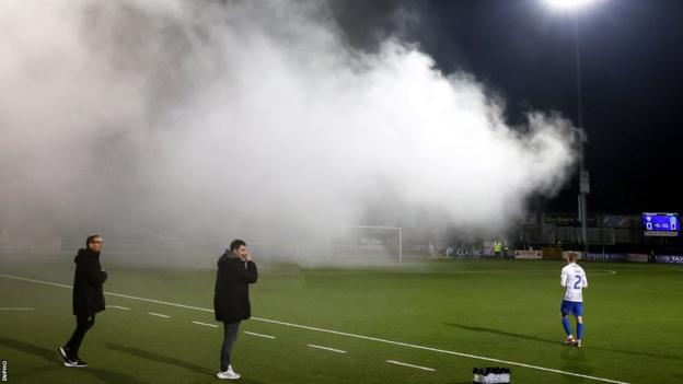 The second half of Linfield's game away to Coleraine was delayed after flares were let off at the Showgrounds