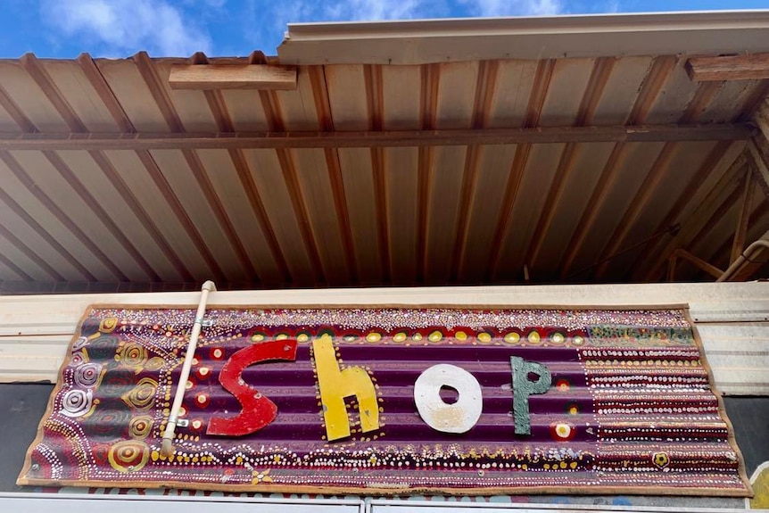 An arty sign says 'shop' on corrugated iron